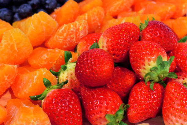 Strawberries, oranges and blueberries are beautifully arranged.