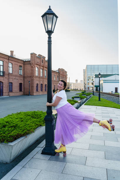 Young woman in a tulle skirt and white t-shirt rollerskating in summer