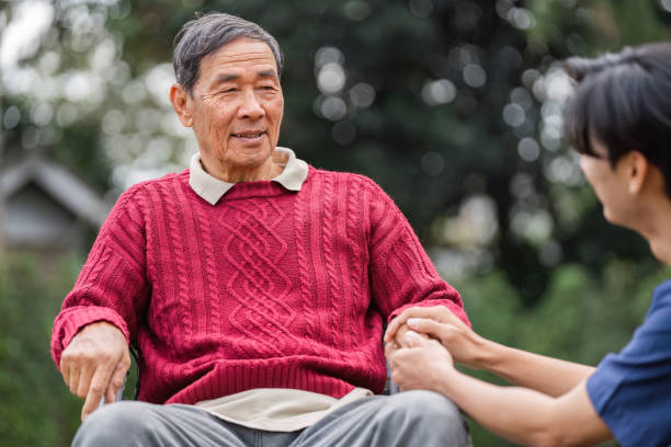 istock Elderly man enjoying conversation with caregiver outdoors during a sunny day in a tranquil garden 2196719433