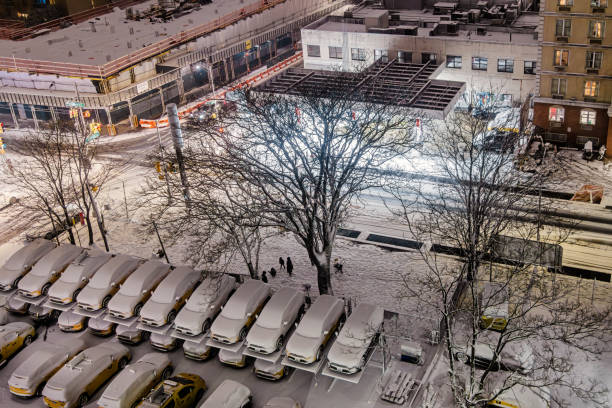 Long Island City, Queens, New York, United States - January 19th 2025:  Parking lot with yellow taxis covered in snow seen from above on a winter night