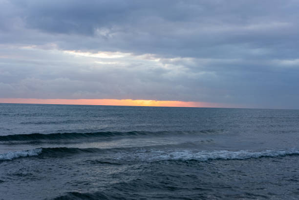 Beautiful sunset among clouds over the sea. Dark blue dramatic Seascape. Sea background.