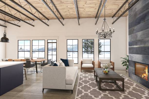 Bright and spacious living area featuring cozy sofas, a fireplace, and large windows showcasing a beautiful wintery landscape. Modern rustic interior with detailed wooden ceiling and elegant decor.