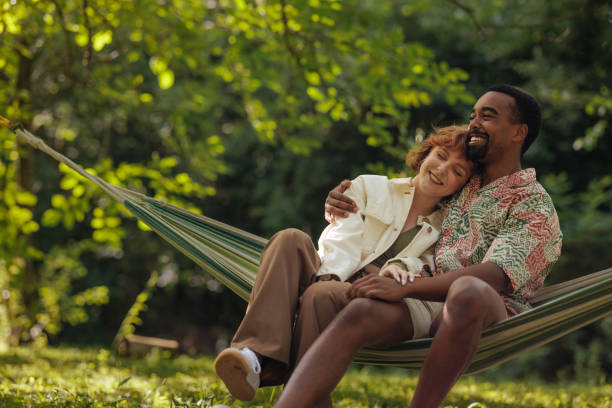 istock Couple relaxing in a hammock inside a park 2196734467