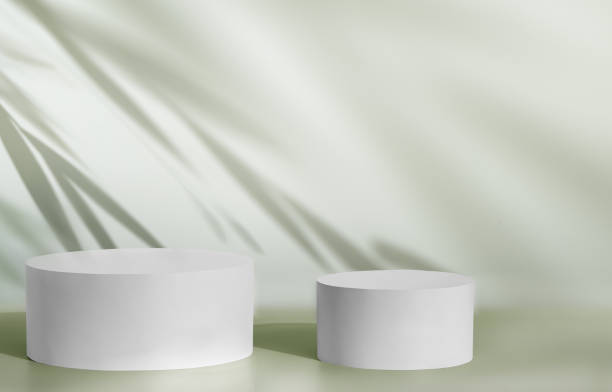 istock White display product pedestals against green wall with soft foliage shadows 2196734504