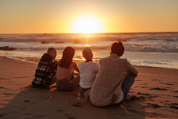 Friends watching golden sunset at beach during summer vacation