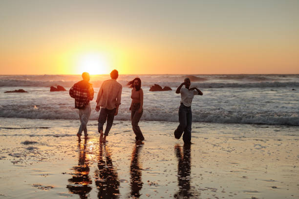 istock Friends walking on beach at sunset enjoying summer vacation 2196735641