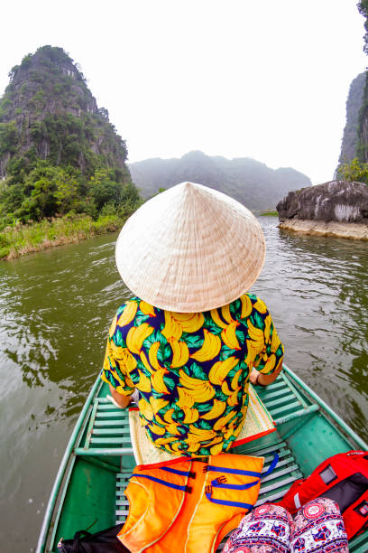 istock Tourist wearing a traditional vietnamese conical hat navigating Tam Coc river in Ninh Binh, Vietnam 2196741839
