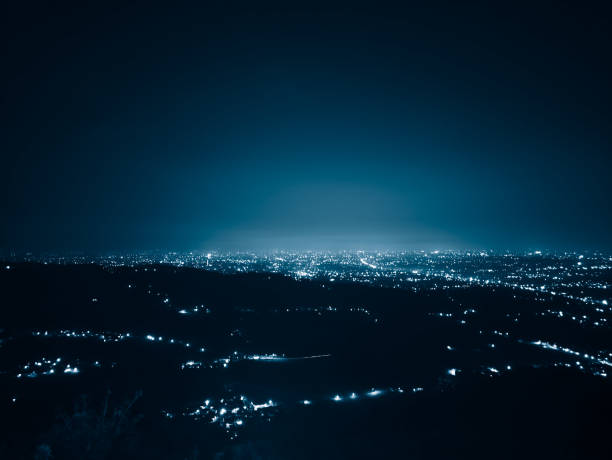 Panoramic view of a city's glowing lights sprawling under a tranquil, starless night. The illuminating cityscape conveys serenity and urban vibrancy.