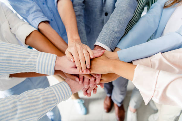 istock Group of colleagues joining hands together expressing teamwork in a bright office setting 2196745150