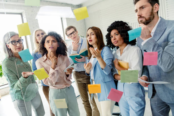 istock Diverse coworkers discussing ideas in an office environment with focused expressions and post-it notes 2196745311