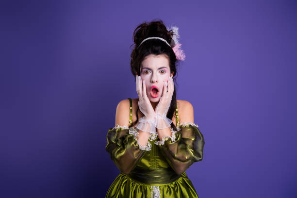 istock Young woman dressed in baroque costume with a surprised expression, posing against a vibrant purple background 2196745478