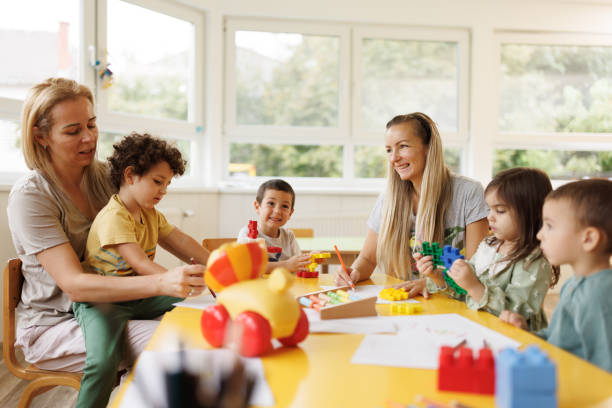 istock Children and their teachers sit at a table while drawing and playing in the kindergarten 2196745608