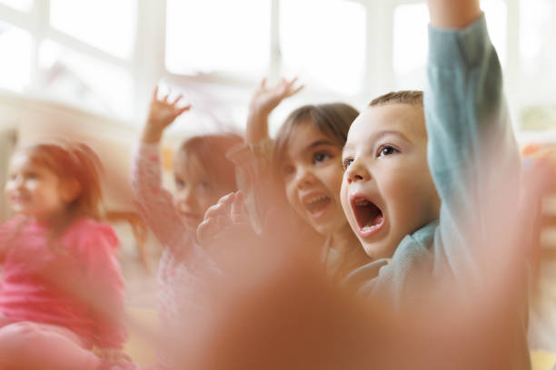 Close-up of a group of small children with their hands raised in a kindergarten