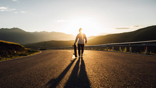 istock Skateboarder skateboarding on the sunset mountain top road 2196746593