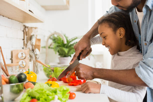 istock Cropped image of black father and daughter cutting vegetables 2196749355