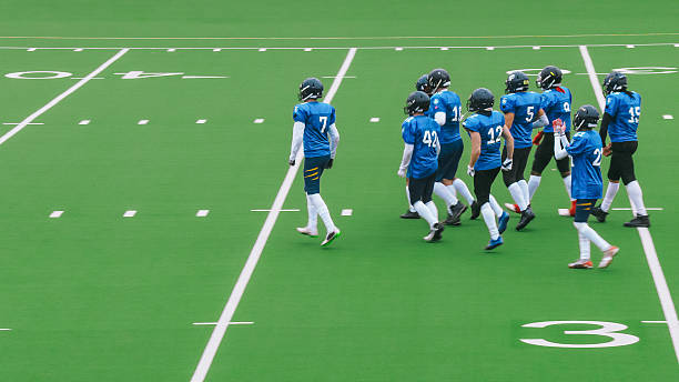This is a photo of football players holding up muddy helmet to the air in victory after a game.