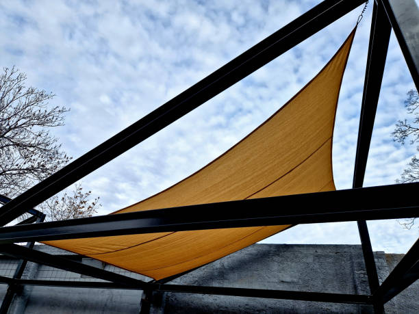 square canvas stretched, shading from sun, rain over terrace ofrestaurant, playground in kindergarten, platform of promenade. pergola with metallic gray beams , cable, electric, bulb,