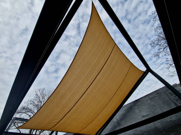 square canvas stretched, shading from sun, rain over terrace ofrestaurant, playground in kindergarten, platform of promenade. pergola with metallic gray beams , cable, electric, bulb,