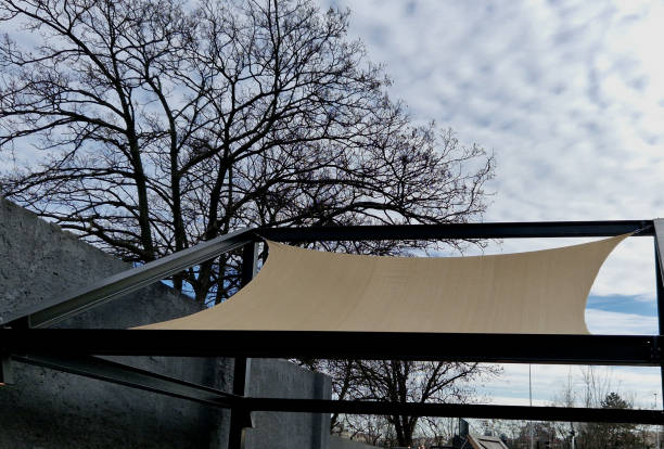 square canvas stretched, shading from sun, rain over terrace ofrestaurant, playground in kindergarten, platform of promenade. pergola with metallic gray beams , cable, electric, bulb,