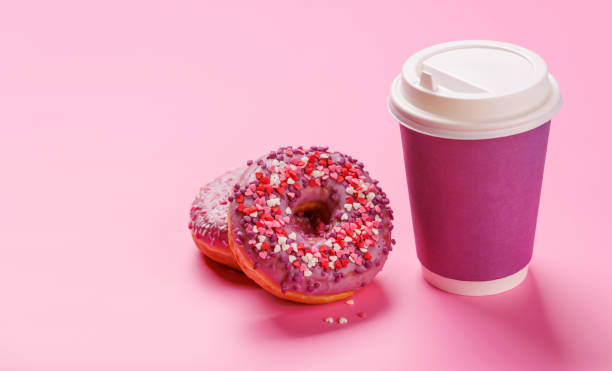 istock A cheerful display of donuts and a paper coffee cup on a pastel pink background 2196751097