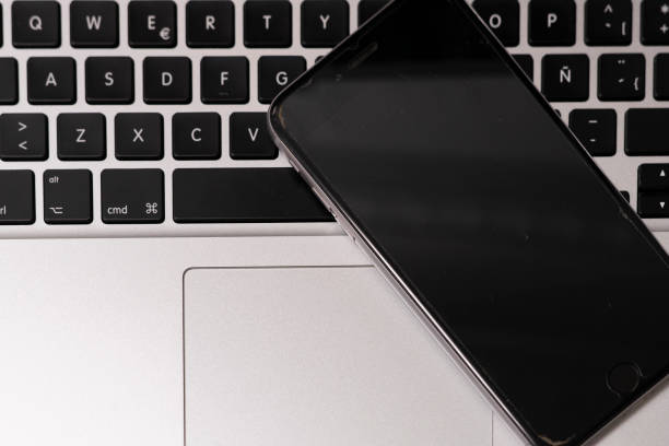 Smartphone on the keyboard of a modern laptop close-up.