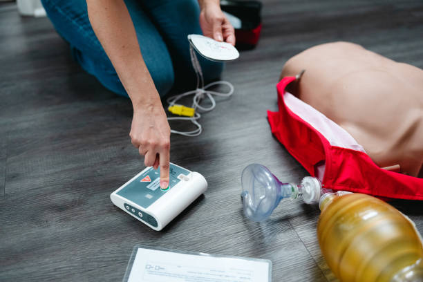 An unrecognizable woman kneels on the floor of a dental office, using medical instruments during a CPR training.