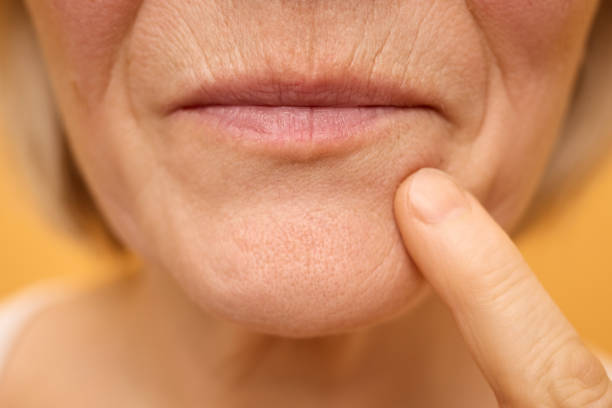istock An older woman is softly touching her chin with her finger, showing a thoughtful expression. The warm background enhances the intimate moment, suggesting contemplation or memory 2196754920