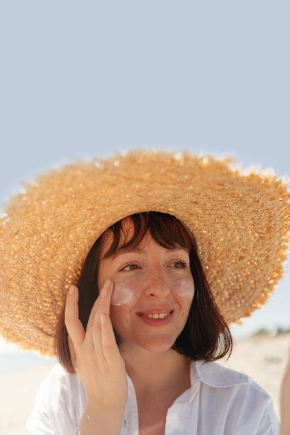 istock Young woman applying sunscreen at the beach 2196756950