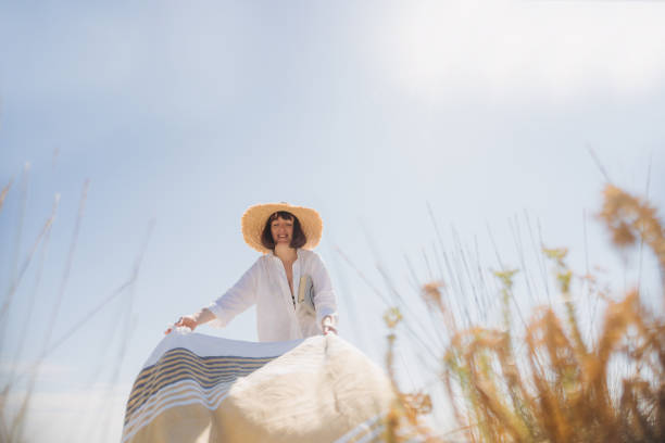 Portrait of a smiling woman at the beach, setting up her beach towel