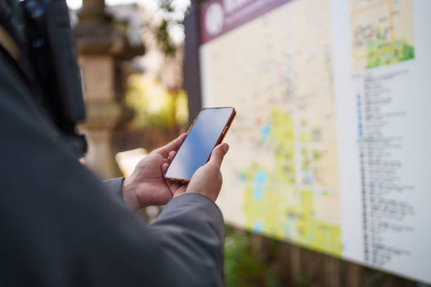 istock Close-up shot of a hand using a phone in front of a map board. 2196758775