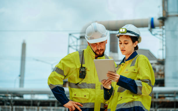 istock Engineers collaborating at an industrial site while reviewing project plans on a tablet in bright safety gear 2196758862