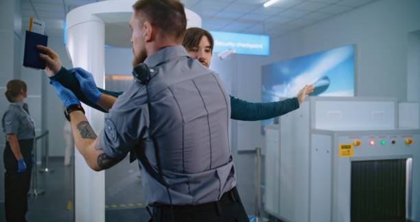 istock Man Walks Through Metal Detector Gates. Security Officer Inspects Passenger, Checks Documents 2196759898