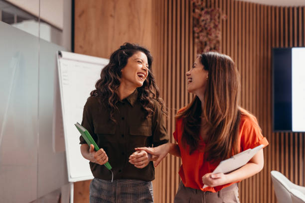 istock Two businesswomen laughing together while walking in the office 2196760505
