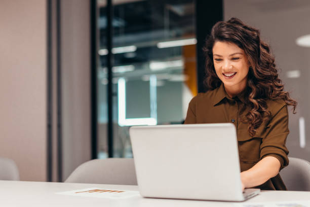 istock Smiling businesswoman working on laptop in modern office 2196764363