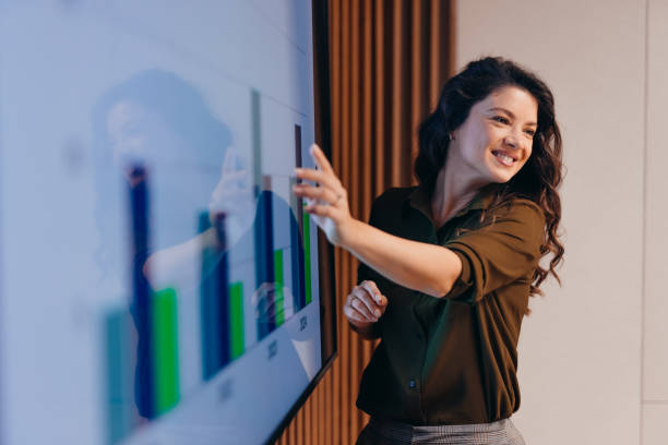 Young businesswoman pointing at interactive whiteboard during a presentation smiling