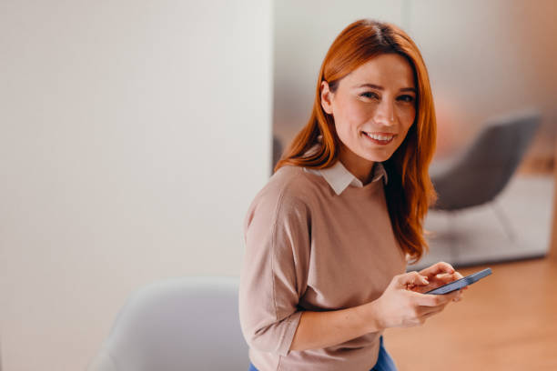 istock Smiling businesswoman using smartphone in modern office 2196764817