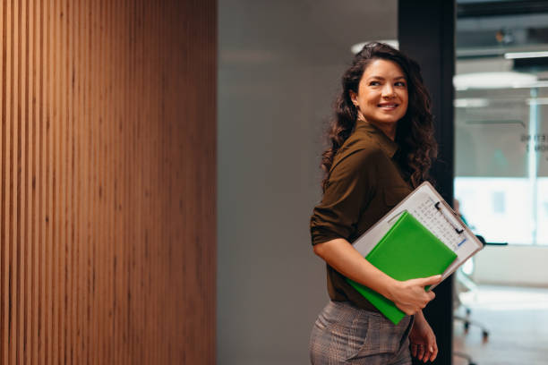 istock Businesswoman smiling and holding documents in modern office 2196765257