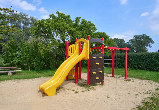 istock Colored climbing frame with slide on a sandy area surrounded by hedges and trees 2196766104