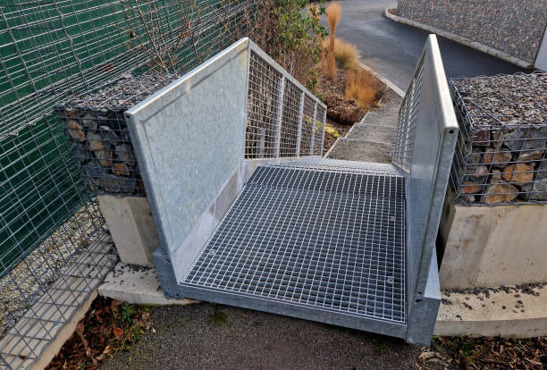 istock construction of a steep staircase by stone wall car park with high durability even under heavy load galvanized steel floor grate and railings. gabion above him wire fence. corridor, flowerbed 2196767559