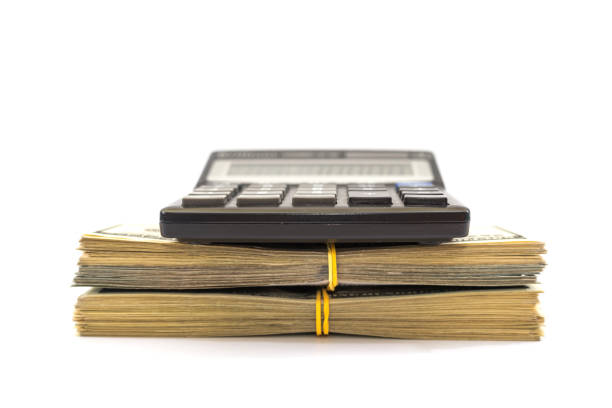 Bundles of dollars and a calculator on a white background. Side view.
