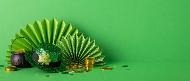 Green backdrop featuring St. Patrick's themed decorations including a glittery hat, pot of gold, gold coins, and paper fans representing Irish traditional holiday celebrations and festive spirit