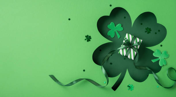 istock Decorative green background featuring a small gift box with ribbons amidst shamrock motifs 2196774594