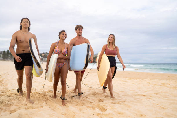 istock Group of Friends Walking with Surfboards on a Sandy Beach 2196776881