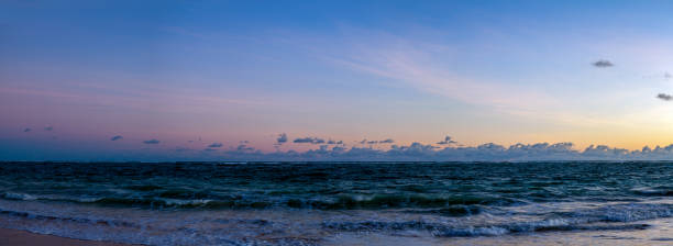 Clouds, sea, ocean, sand, water, boats in silhouette.