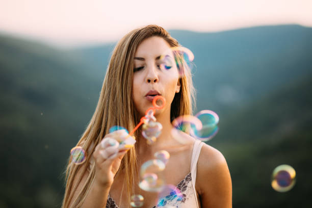 istock Beautiful Young Woman Blowing Soap Bubbles Outdoors on a Summer Day 2196777864