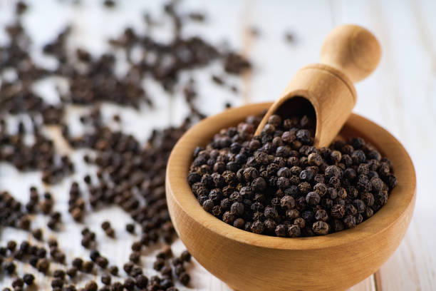 istock black pepper seeds in a wooden bowl on a light kitchen table, selective focus. 2196779231