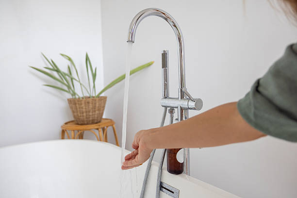 istock Woman Testing Water Temperature in a Modern Bathroom 2196780860
