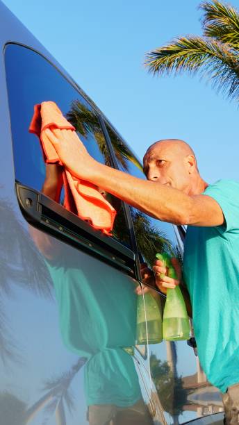 istock Mature hispanic man washing his car window with microfiber cloth and spray bottle 2196783079