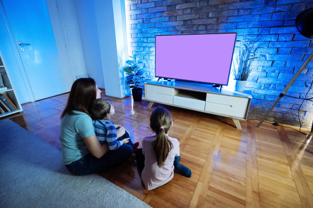 istock Mother with two children watching TV at home 2196785805