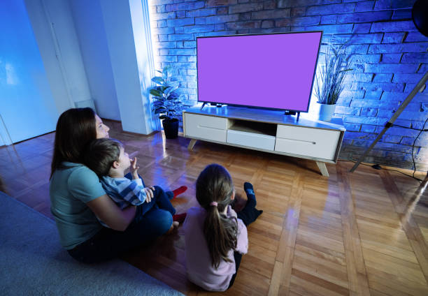 istock Mother with two children watching TV at home 2196785880